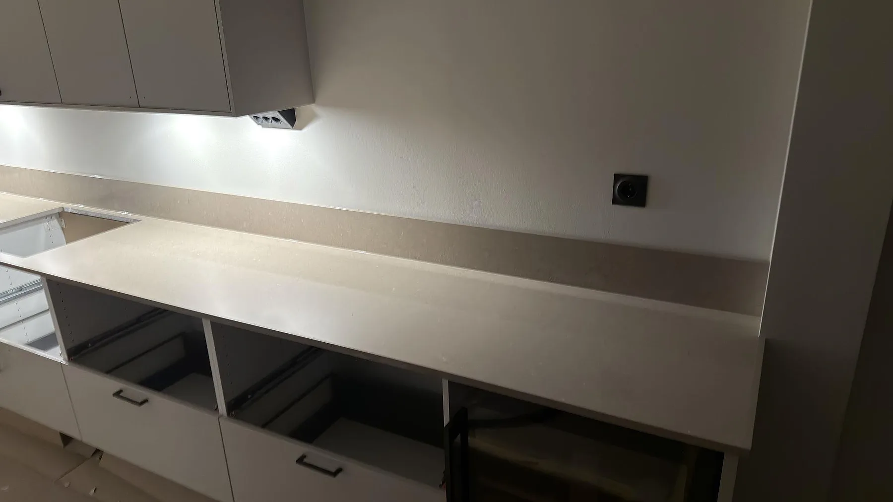 Detalj av polerad köksbänkskiva i Silestone Coral Clay med uppvikt stänkkant i 12 mm längs väggen i ett kök i Skogås.