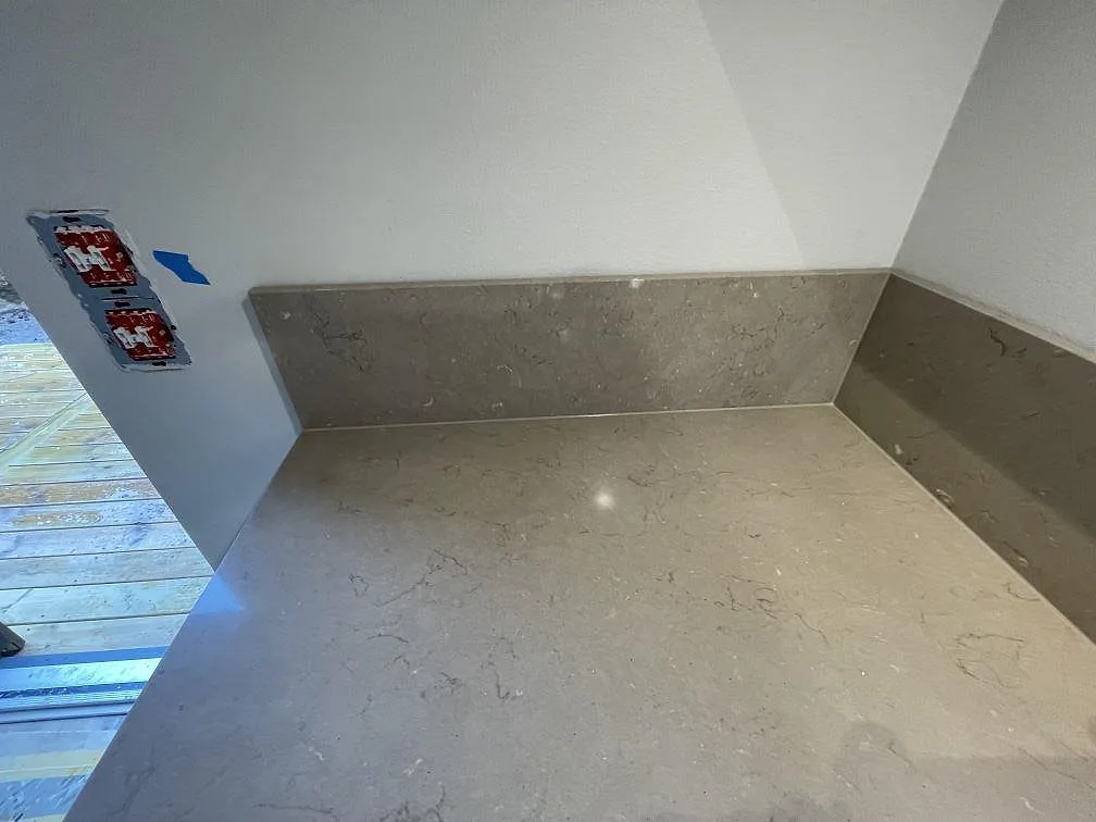 Greige Silestone Coral Clay bänkskiva med uppvikt stänkkant och matchande stänkskydd i ett kök i Skogås, fotat under montering.