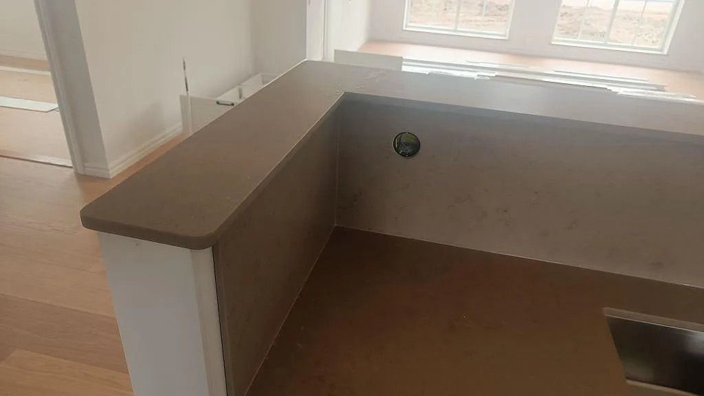 Sidovy av Silestone Coral Clay bänkskiva och stänkskydd vid fönster, monterad som halvö i ett kök i Skurup.