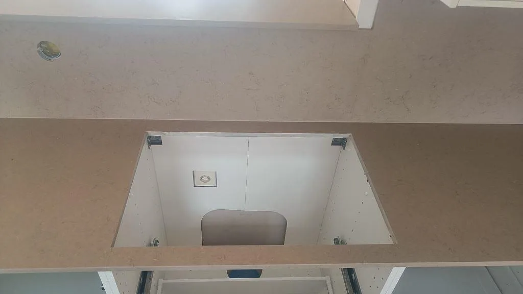 Hällöppning i Silestone Coral Clay köksbänkskiva i Mocka-finish, med vitt skåp och stänkskydd bakom i Skurup.