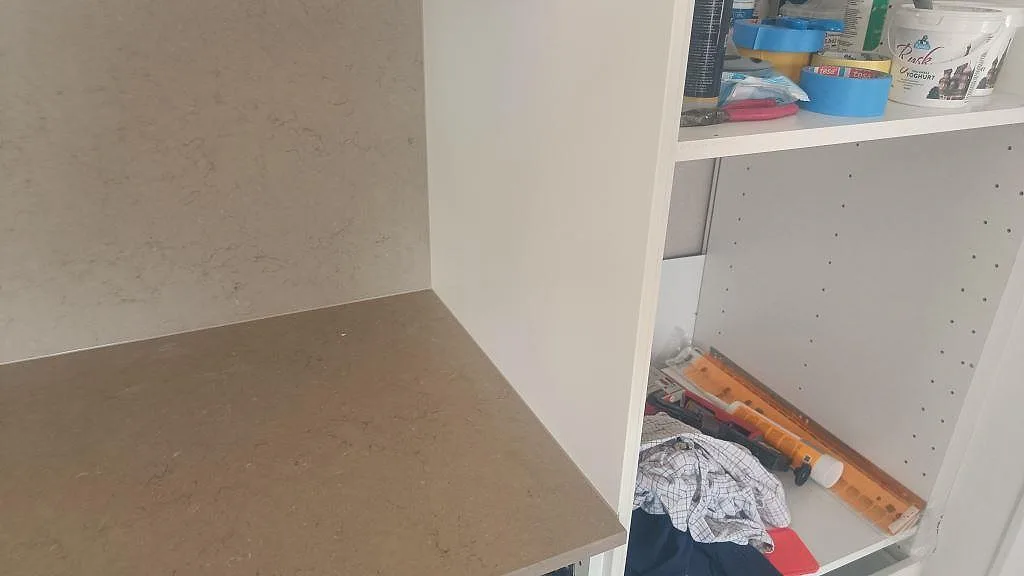 Detalj av Silestone Coral Clay köksbänkskiva i Mocka-finish vid öppna vita köksstommar under montering i Skurup.