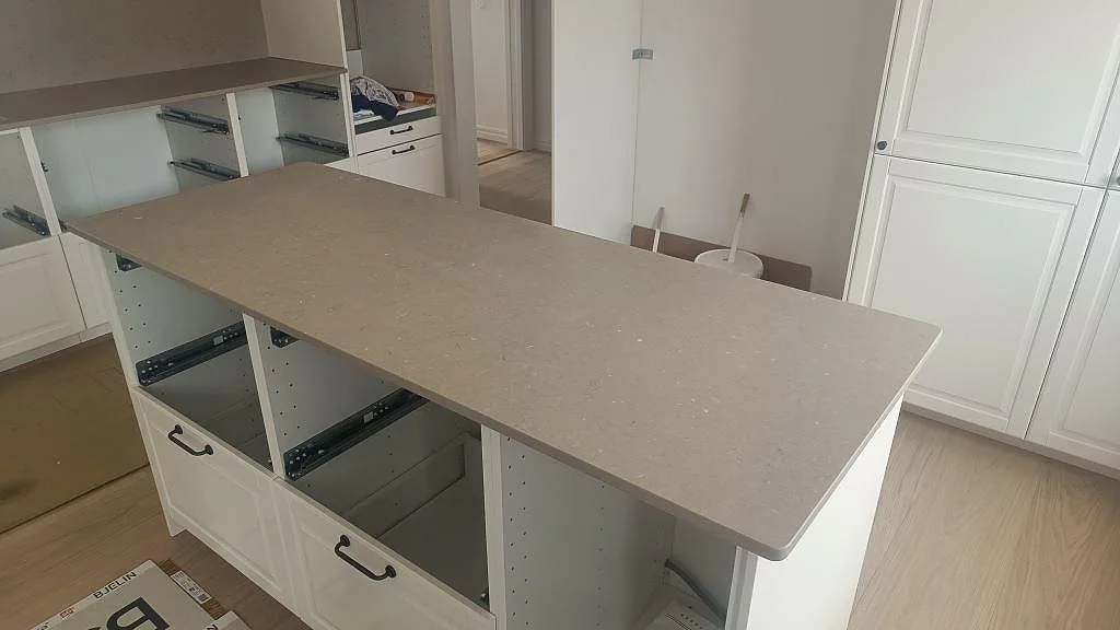 Halvö med köksbänkskiva i Silestone Coral Clay kvartskomposit, matt Mocka-yta och rundad kant i kök under montering i Skurup.