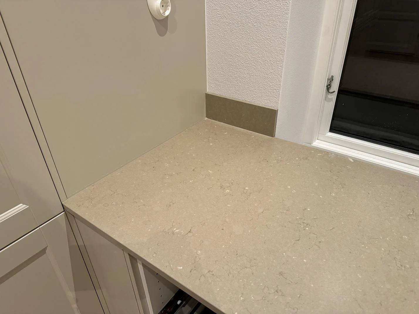 Installerad köksbänkskiva i Silestone Coral Clay, Mocka, med uppvikt stänkkant intill fönster och vägg i Skurup.