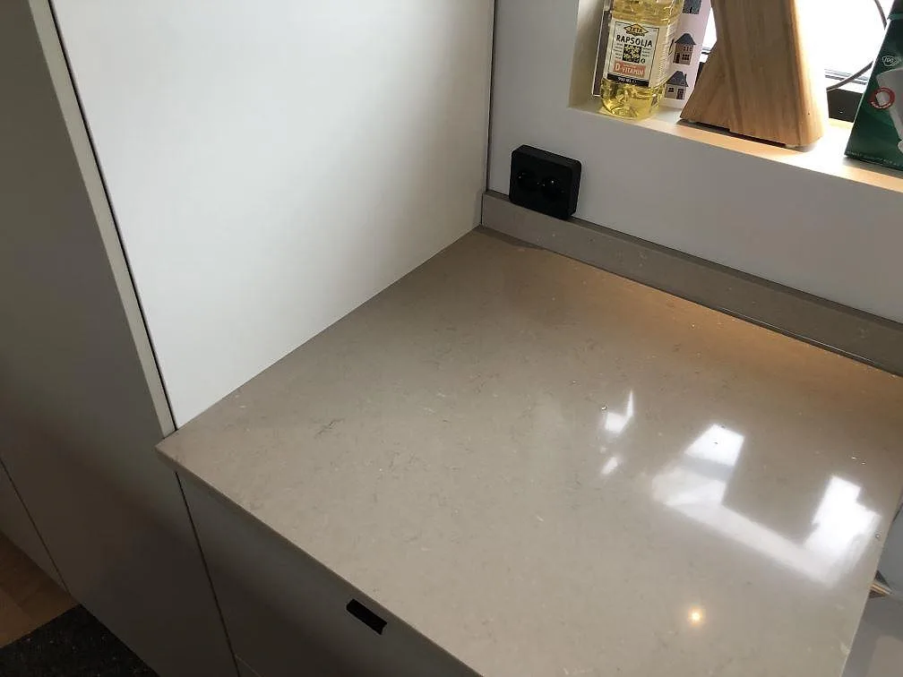 Bänkskiva i Silestone Coral Clay mot fönstret med matchande fönsterbänk och stänkkant i samma sten i ett kök i Sölvesborg.