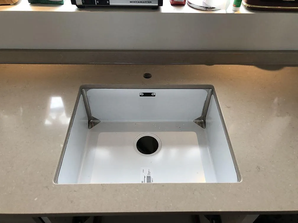 Underlimmad vit diskho i köksbänkskiva av Silestone Coral Clay med förborrat blandarhål i ett kök i Sölvesborg.