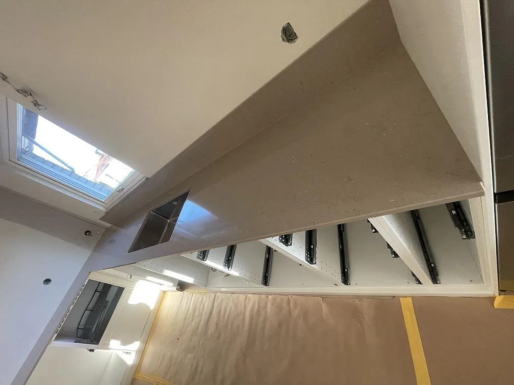 Bänkskiva i Silestone Coral Clay med urtag för häll längs väggen i ett kök under montering i Sölvesborg.