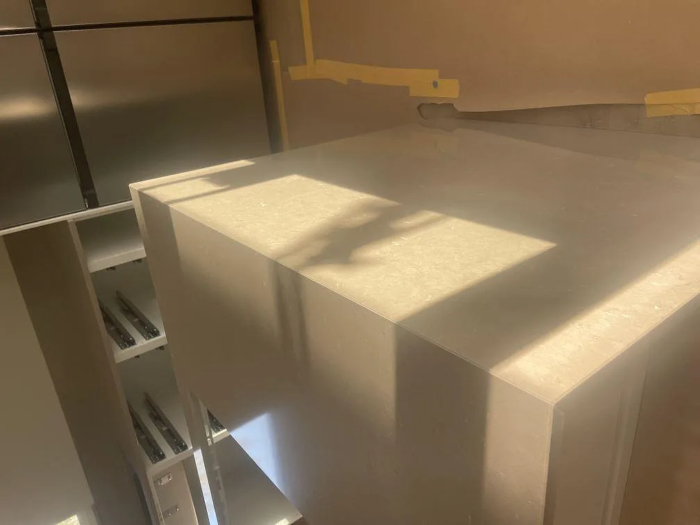 Polerad köksö i Silestone Coral Clay med gerad vattenfallskant och mjuk ljusreflex i ett kök i Sölvesborg.