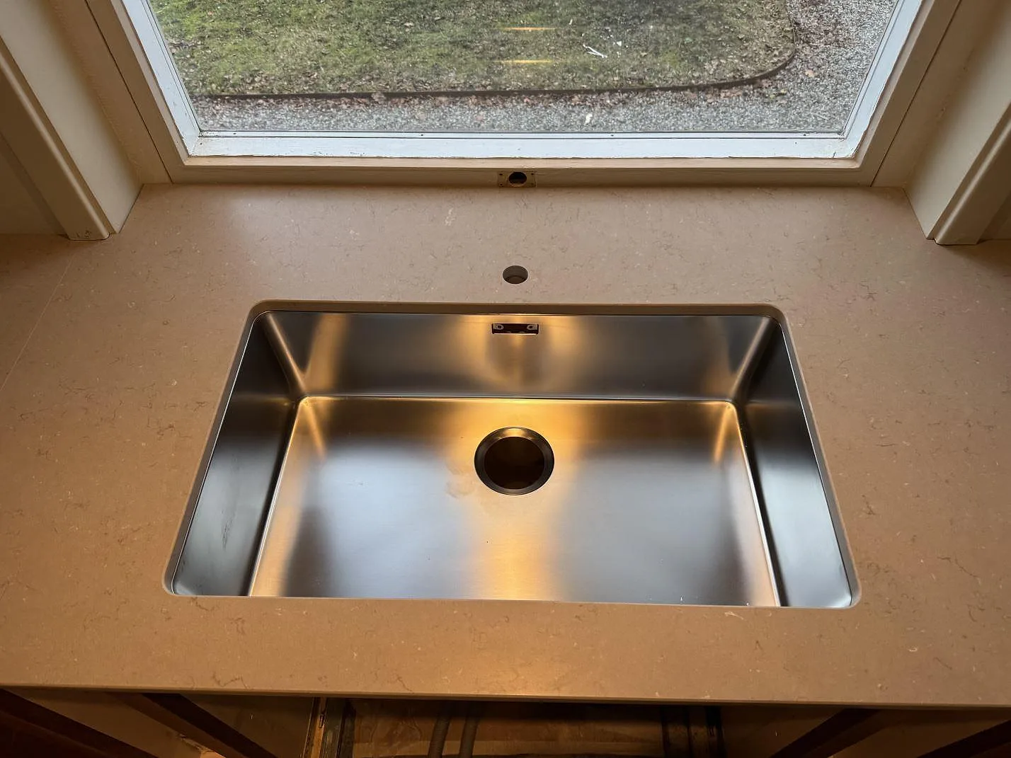 Underlimmad rostfri diskho i köksbänkskiva av matt Silestone Coral Clay, monterad under fönster i Sösdala.