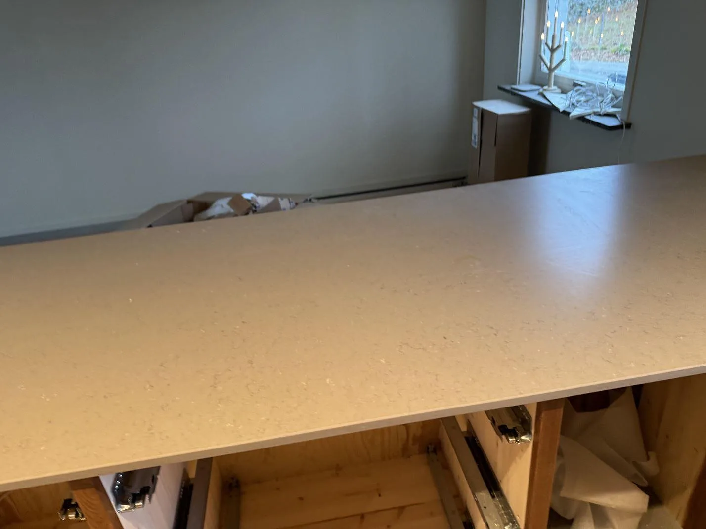 Lång arbetsyta på köksö i matt Silestone Coral Clay, 20 mm kvartskomposit, i ett kök under montering i Sösdala.
