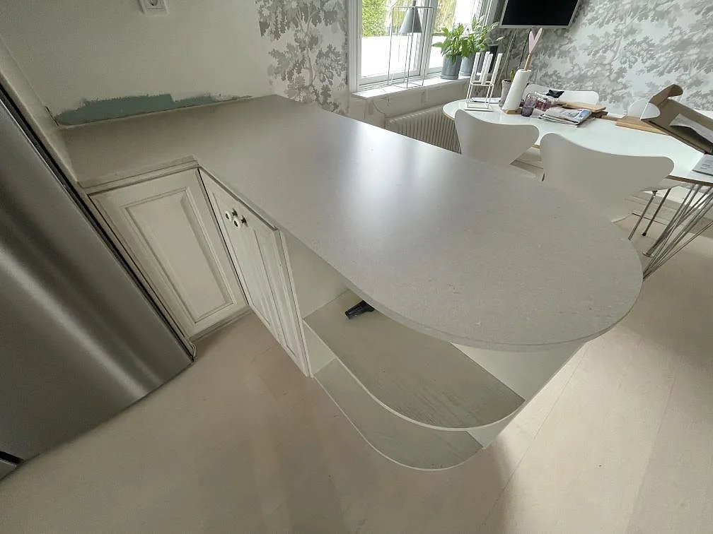 Närbild av rundad köksö i matt Silestone Coral Clay, 12 mm Mocka, monterad mot vita köksluckor i Sollentuna.
