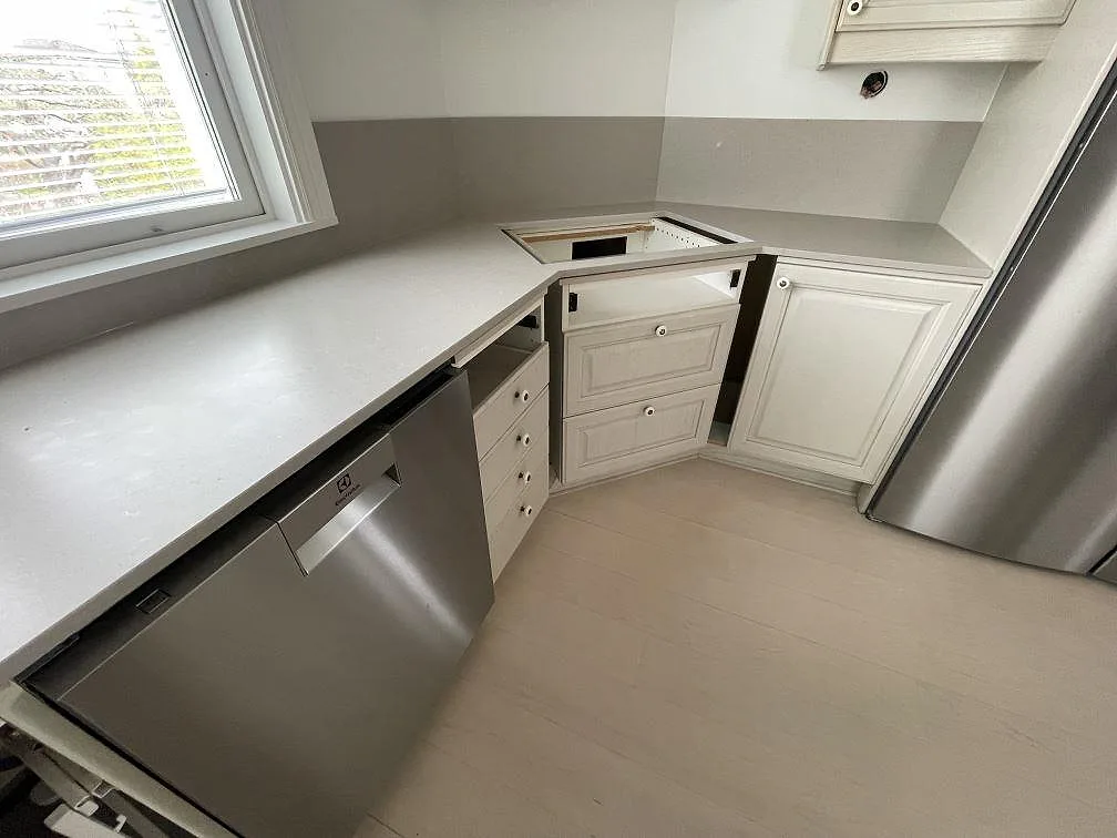 Hörnmonterad bänkskiva i matt Silestone Coral Clay med förberedd öppning för häll och låg stänkkant i Sollentuna.