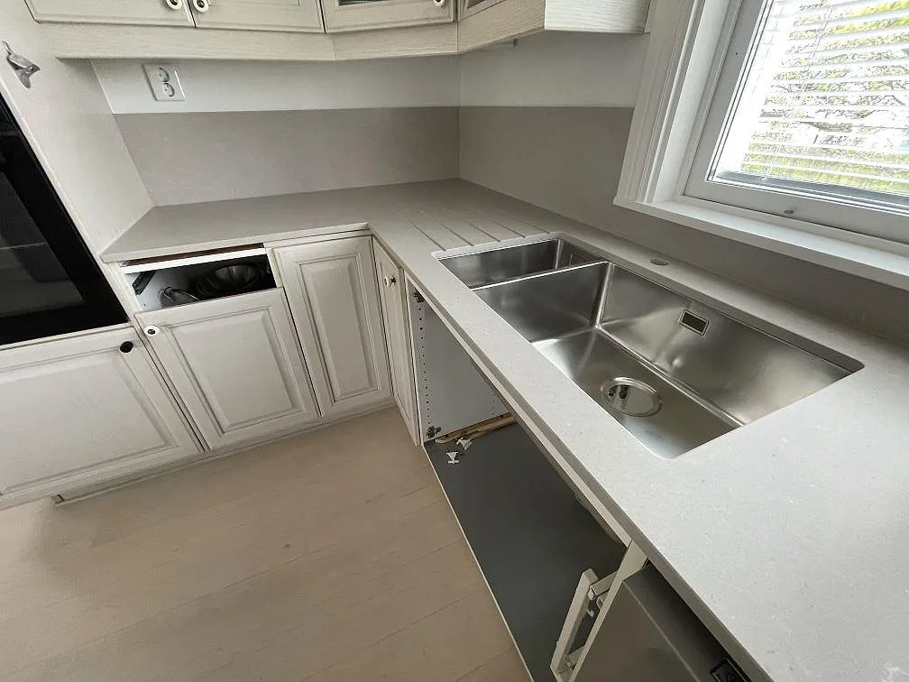 Köksbänkskiva i matt Silestone Coral Clay med rostfri diskho, låg stänkkant och öppna stommar under montering i Sollentuna.