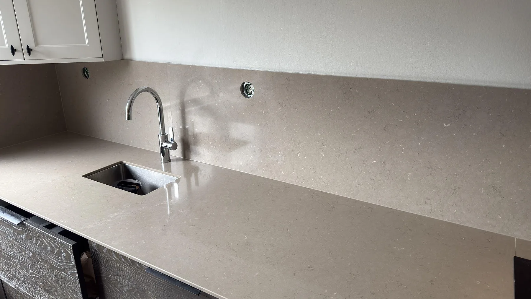 Detalj av underlimmad rostfri diskho och köksblandare på en köksbänkskiva i polerad Silestone Coral Clay i Sollentuna.