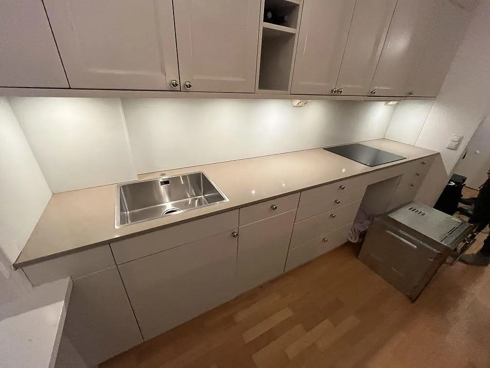 Bänkskiva i polerad Silestone Coral Clay, 20 mm, med rostfri diskho och svart häll längs väggen i Solna.