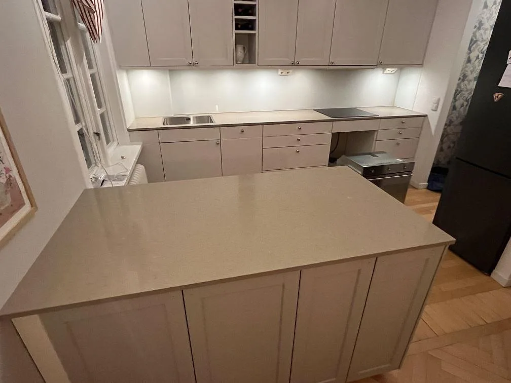 Köksö och bänkskivor i polerad Silestone Coral Clay, 20 mm, i ett kök med ljusa luckor i Solna.