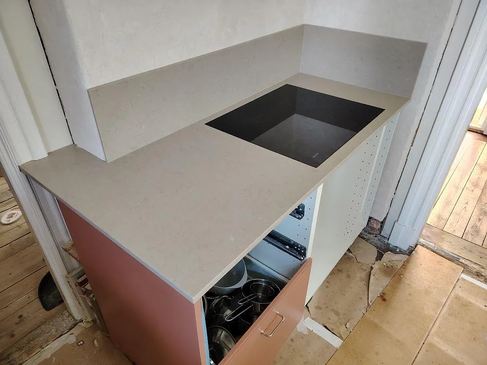 Detalj av köksbänkskiva i Silestone Coral Clay, matt Mocka, med svart häll och uppvikt stänkskydd i Spånga.