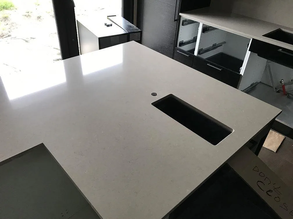 Köksö i Silestone Coral Clay med urtag för diskho och häll i ett kök i Staffanstorp, öppna köksstommar i bakgrunden under montering.