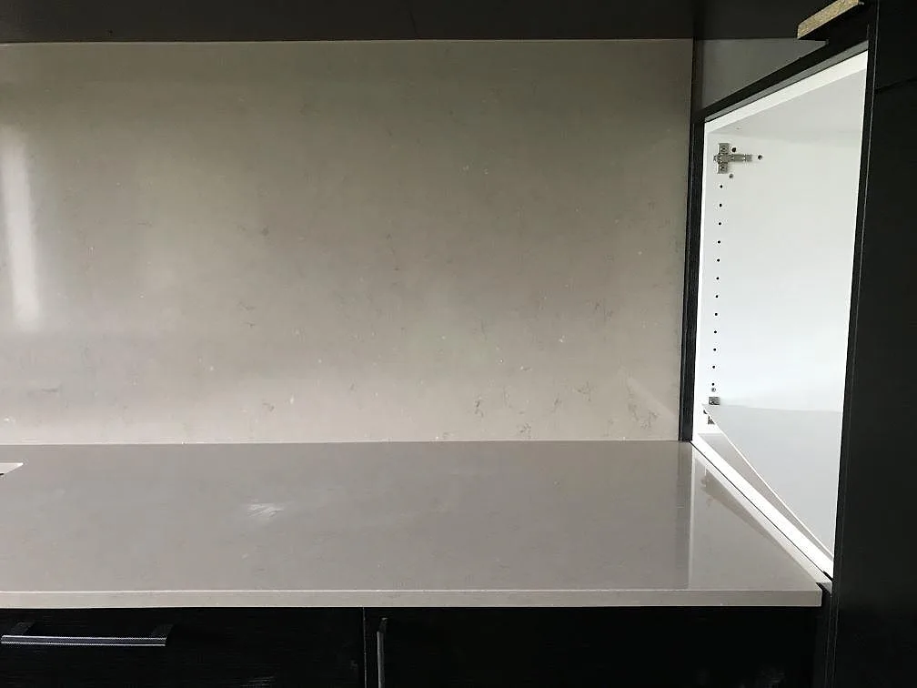 Köksbänkskiva i Silestone Coral Clay med uppvikt stänkskydd i samma greige kvartskomposit i ett kök i Staffanstorp.