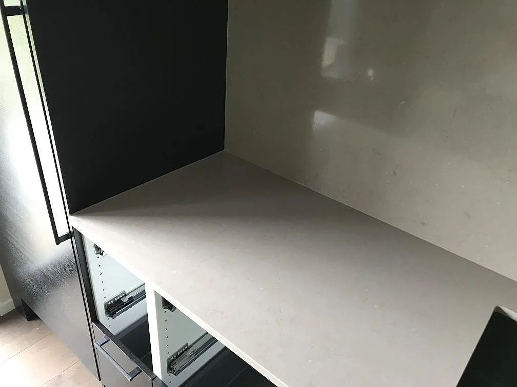 Hörnparti av köksbänkskiva i Silestone Coral Clay ovanför öppna lådstommar i ett kök i Staffanstorp under montering.