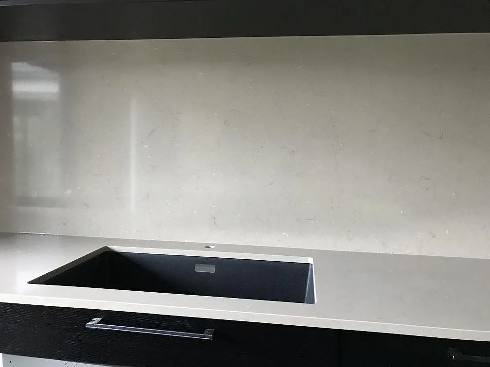 Perimeterbänk i Silestone Coral Clay med underlimmad svart kompositdiskho och matchande stänkskydd i samma sten i ett kök i Staffanstorp.