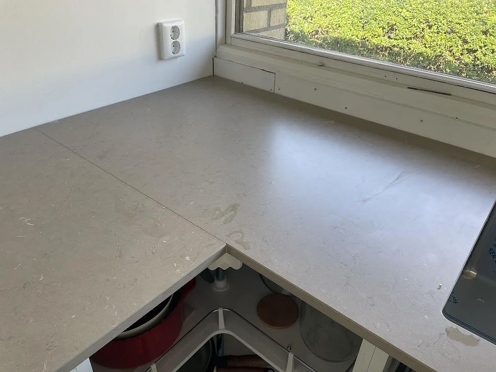 Vinkelbänk i matt Silestone Coral Clay med skarv och fönsterljus över öppna köksstommar i Staffanstorp.