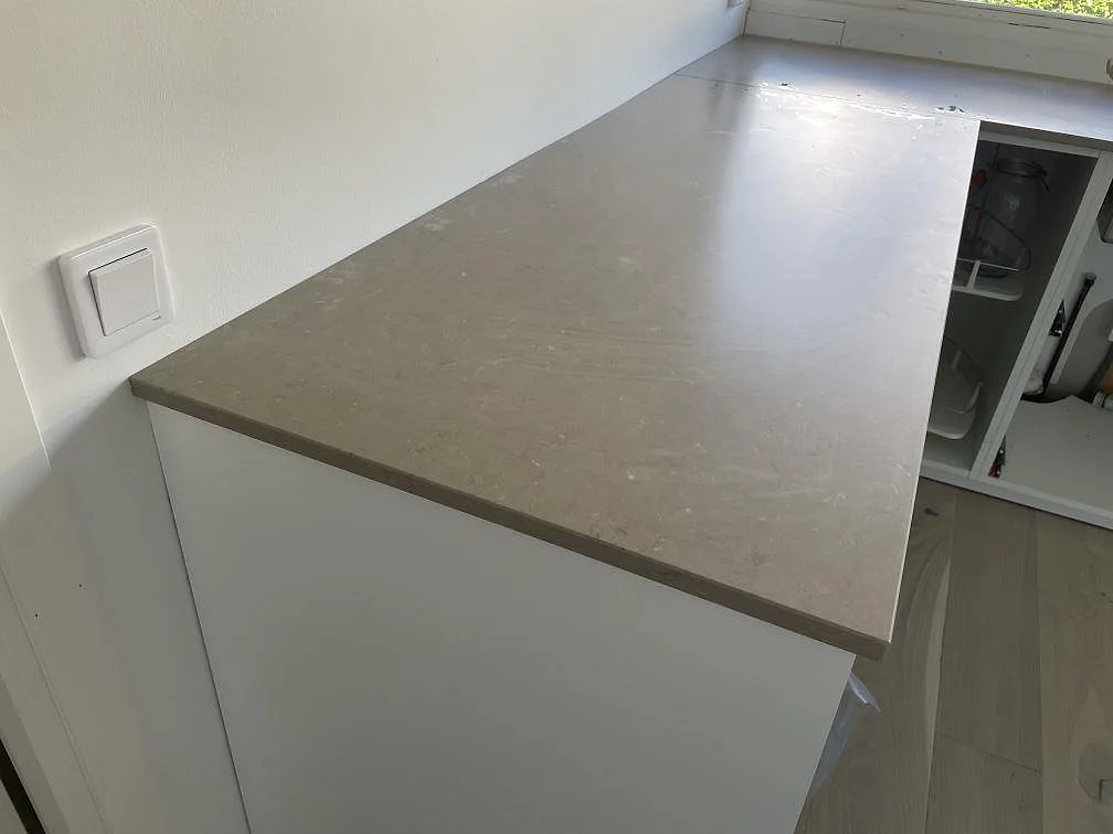 Detalj av matt Silestone Coral Clay bänkskiva med rak framkant ovanpå ljusa stommar i ett kök i Staffanstorp.