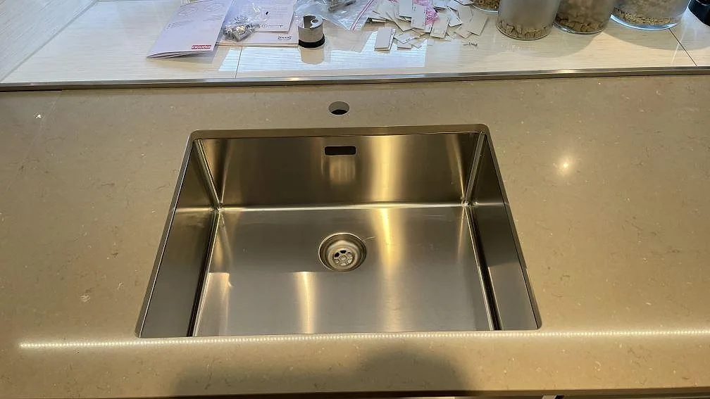 Närbild på polerad Silestone Coral Clay som köksbänkskiva med rostfri diskho och blank yta i Staffanstorp.