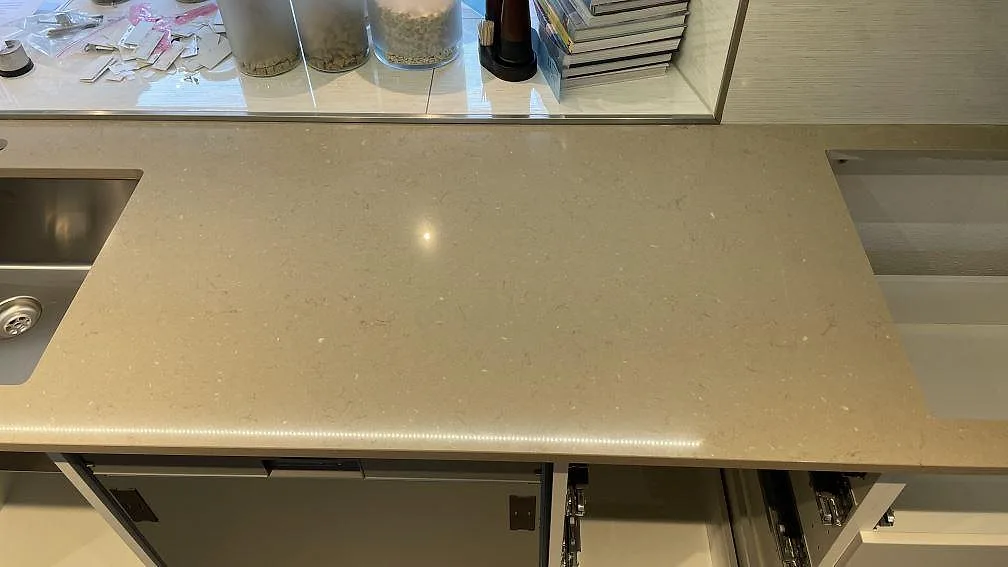 Polerad köksbänkskiva i Silestone Coral Clay mellan rostfri diskho och hällöppning under montering i Staffanstorp.
