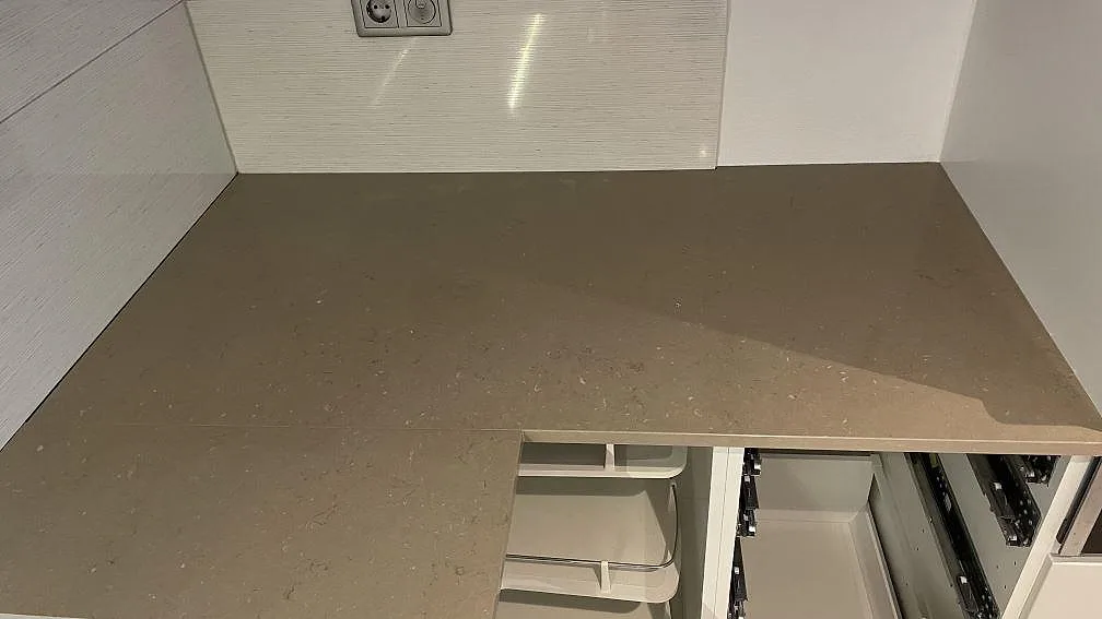 Hörndel av polerad Silestone Coral Clay köksbänkskiva med ljus väggbeklädnad och öppna stommar i Staffanstorp.