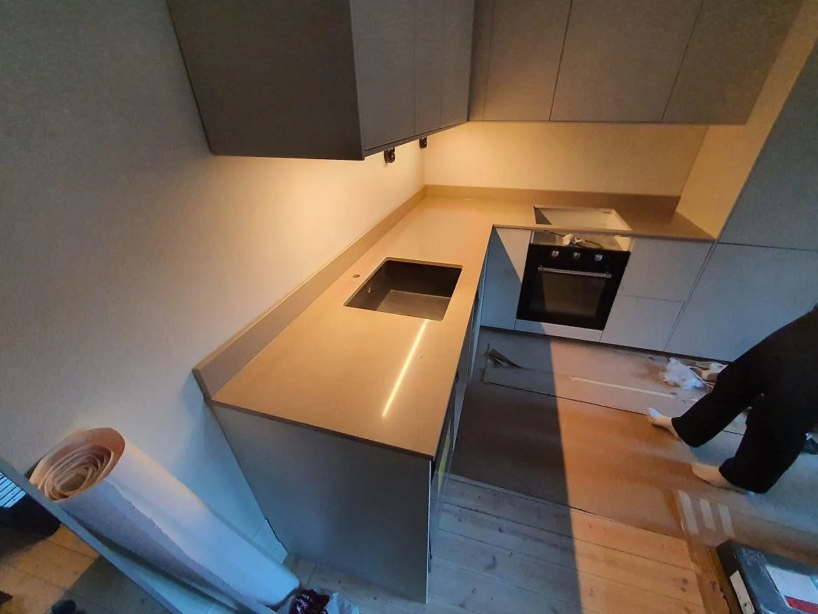 Polerad köksbänkskiva i Silestone Coral Clay, 20 mm komposit, med låg stänkkant i ett kök i Stockholm under montering.