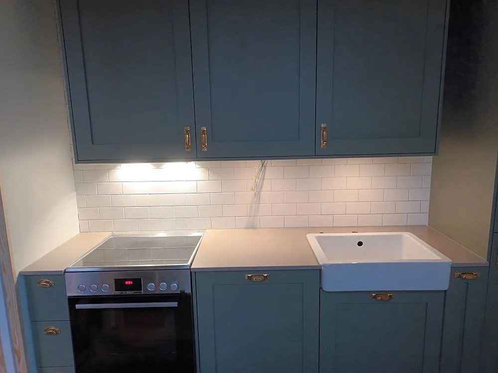 Köksbänkskiva i greige Silestone Coral Clay, matt finish, i ett kök i Stockholm med fristående spis, induktionshäll, vit keramisk lantharsho och vitt kakelstänkskydd.