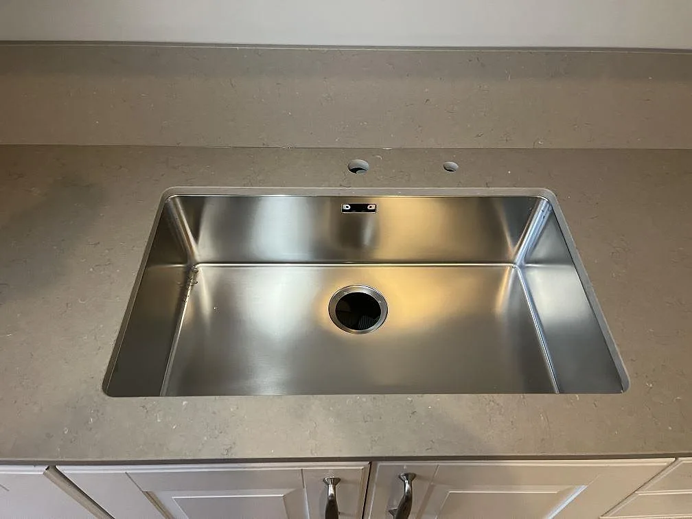 Närbild på underlimmad rostfri diskho i Silestone Coral Clay, matt kvartskomposit med 12 mm stänkkant i ett kök i Stockholm.