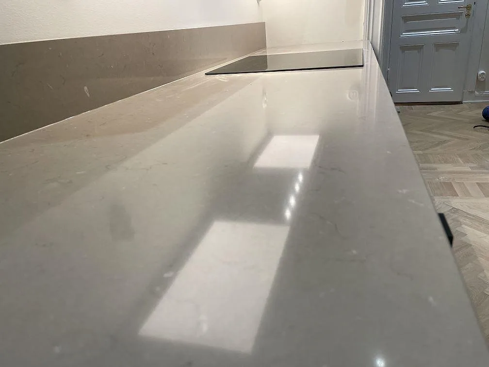 Blankpolerad köksbänkskiva i Silestone Coral Clay med stänkskydd och häll, fotograferad längs arbetsytan i Stockholm.