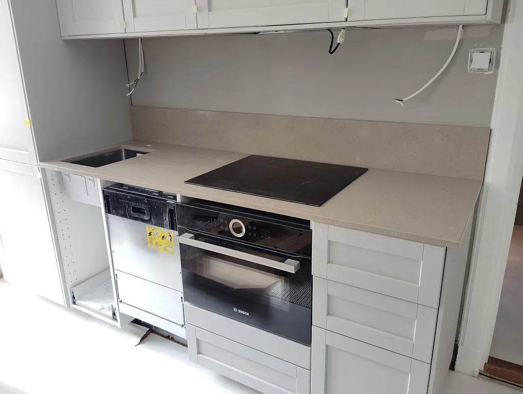 Köksbänkskiva i Silestone Coral Clay, polerad kvartskomposit, med svart häll, underlimmad rostfri diskho och stänkskydd i ett kök i Stockholm.