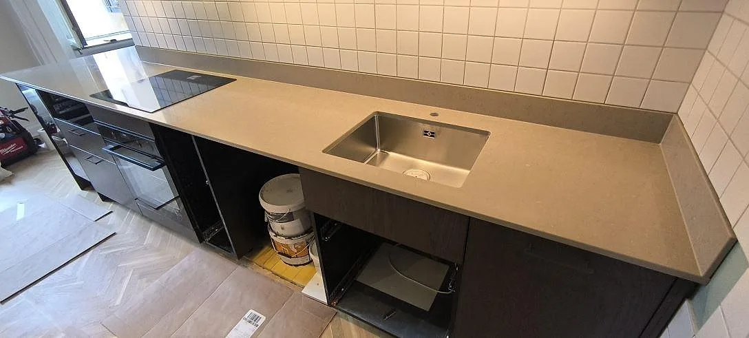 Polerad Silestone Coral Clay komposit som köksbänkskiva med underlimmad rostfri diskho, infälld häll och stänkskydd i Stockholm.