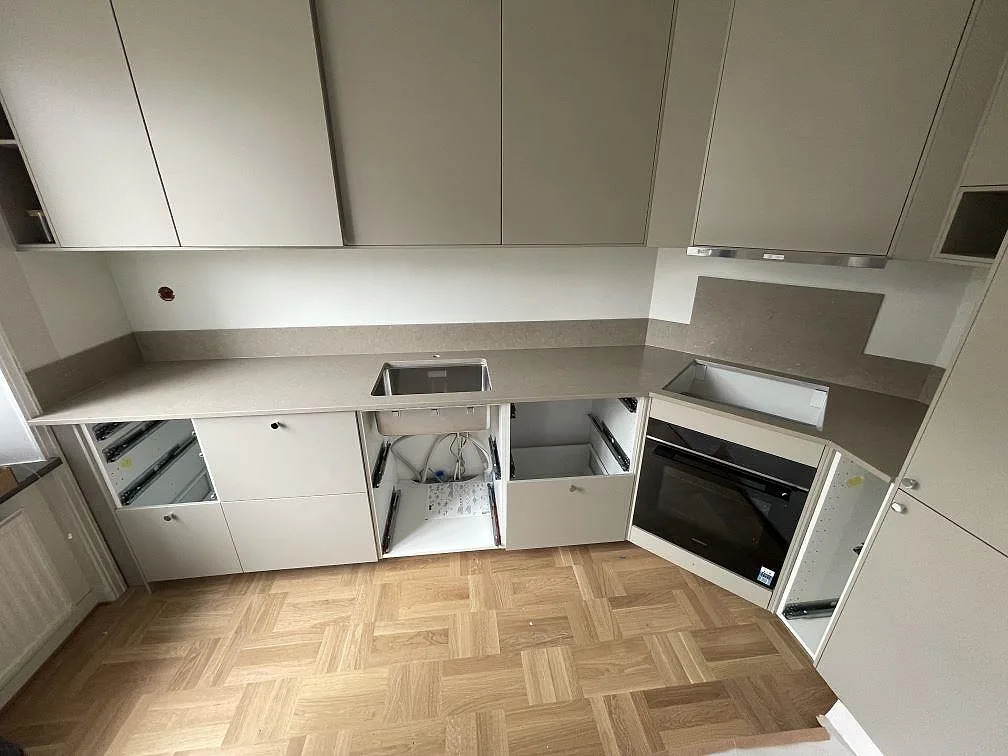 Köksbänkskiva i Silestone Coral Clay kvartskomposit, Mocka, med diskho, hällöppning och stänkskydd under montering i Stockholm.