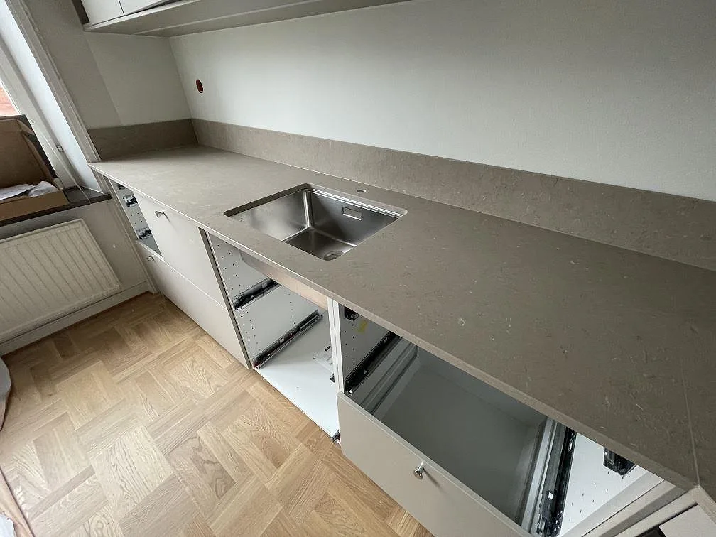 Lång köksbänk i Silestone Coral Clay, matt Mocka-yta, med uppvikt stänkskydd och rostfri diskho i Stockholm.