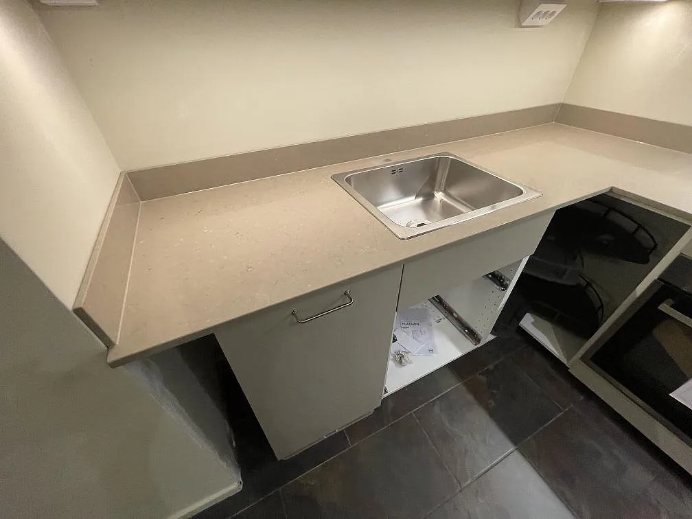 Närbild av polerad Silestone Coral Clay som köksbänkskiva med uppvikt stänkkant och rostfri diskho i Stockholm.