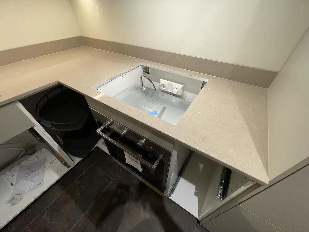 Detalj av hällöppning i polerad Silestone Coral Clay med matchande stänkkant och öppna köksstommar under montering i Stockholm.