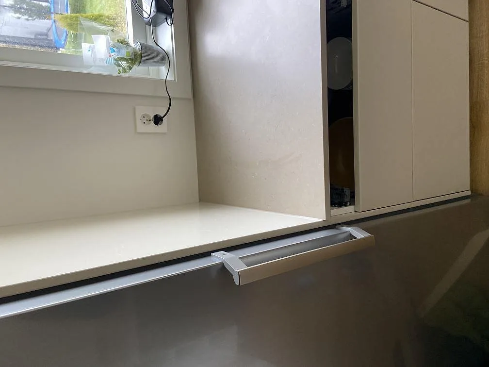 Hög sidopanel i Silestone Coral Clay intill ugnstornet i ett kök under montering i Strömstad.