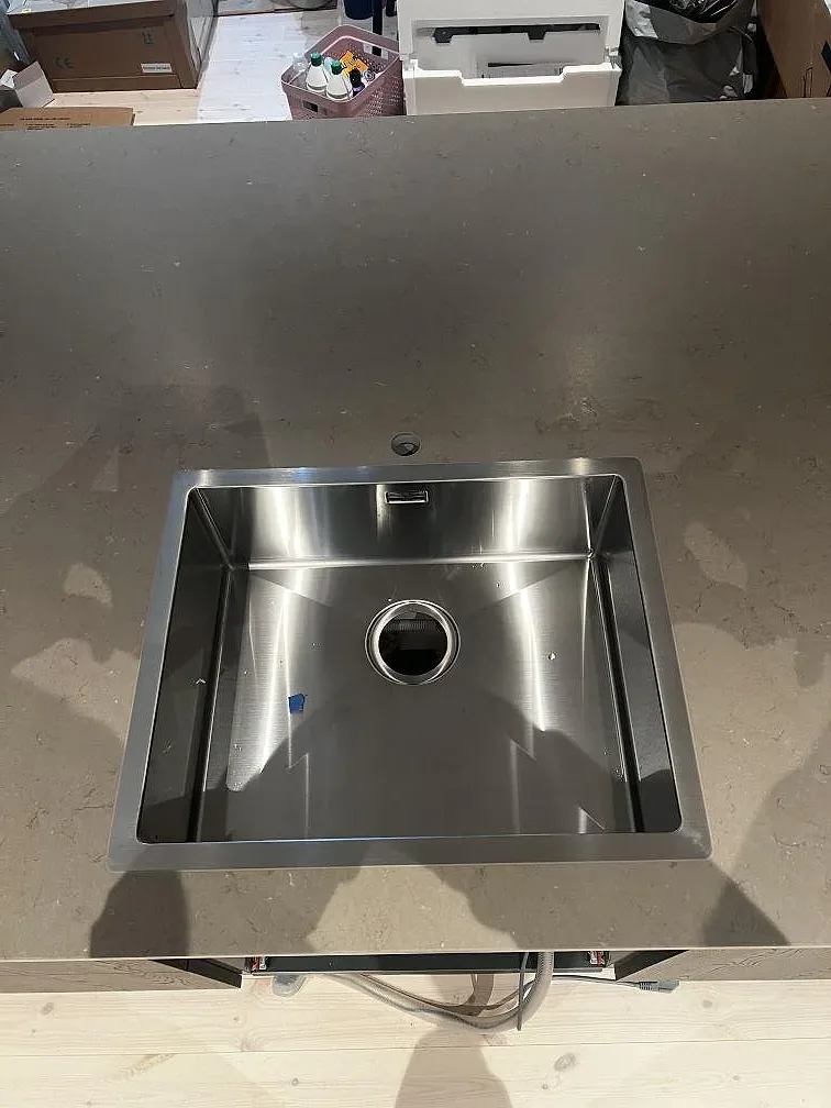 Närbild på matt köksbänkskiva i Silestone Coral Clay med rostfri diskho i ett kök under montering i Strömstad.