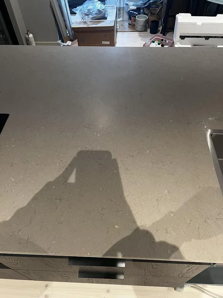 Bred matt arbetsyta i Silestone Coral Clay med gråbeige ton och mörk träfront i ett kök i Strömstad.