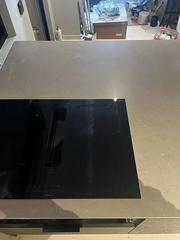 Köksbänkskiva i Silestone Coral Clay med Mocka-yta och svart häll på mörk träinredning i Strömstad.
