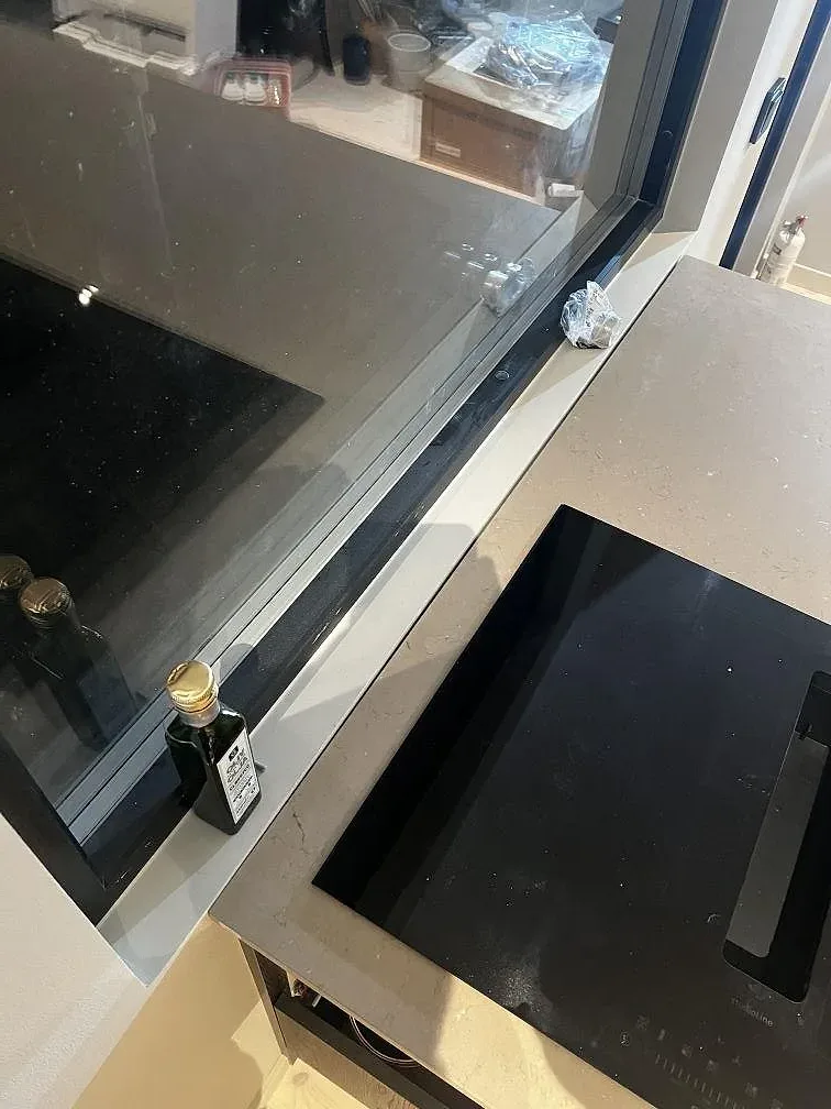 Detalj av svart induktionshäll och matt Silestone Coral Clay vid fönster under köksmontering i Strömstad.