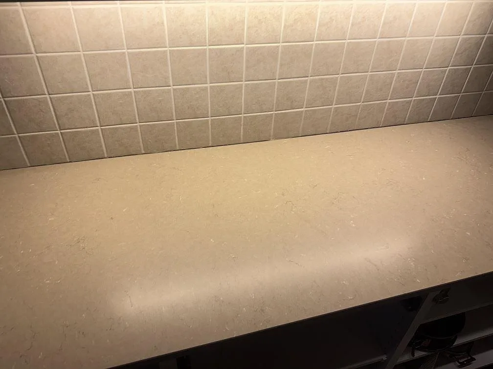 Närbild på matt köksbänkskiva i Silestone Coral Clay med diskret mönstring och kaklat väggparti i Strömstad.