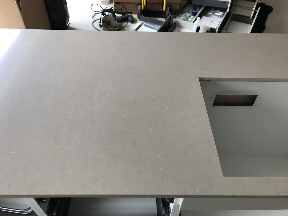 Nedifrån sett köksbänkskiva i Silestone Coral Clay med urtag för häll i ett kök under montering i Svalöv.