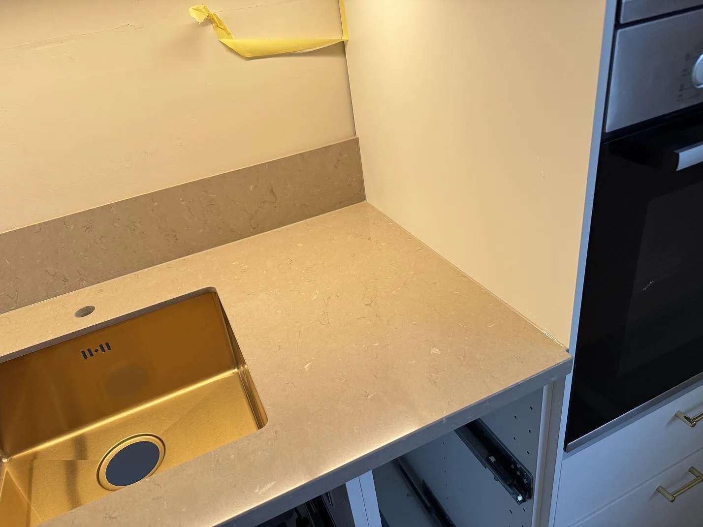 Polerad Silestone Coral Clay bänkskiva i komposit vid en underlimmad diskho och ugnsskåp under montering i Svedala.