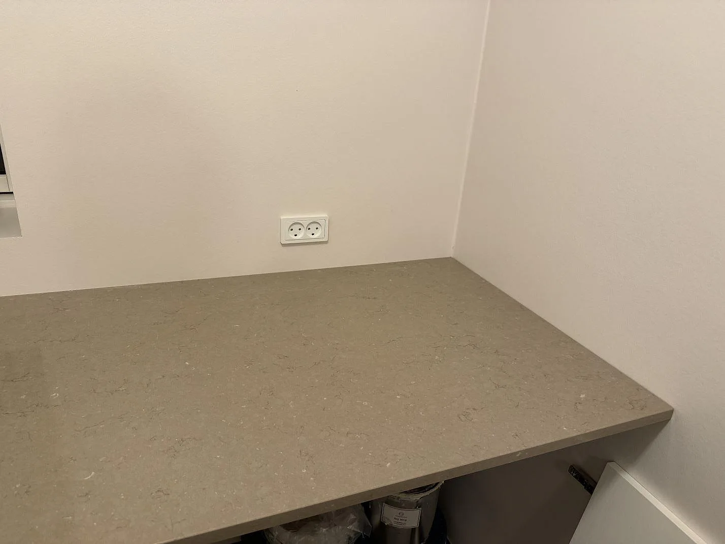 Installerad sidobänk i polerad Silestone Coral Clay mot ljusa väggar, med eluttag ovanför stenen i Svendborg.