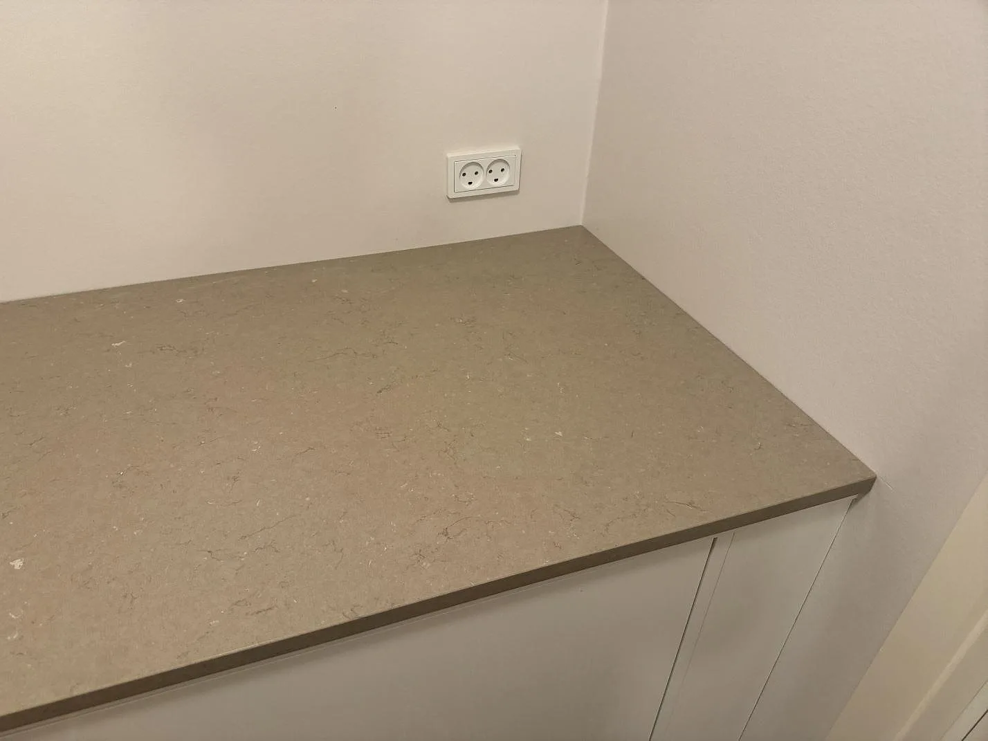 Rak bänkdel i polerad Silestone Coral Clay på vit inredning, med varm gråbeige komposityta i Svendborg.