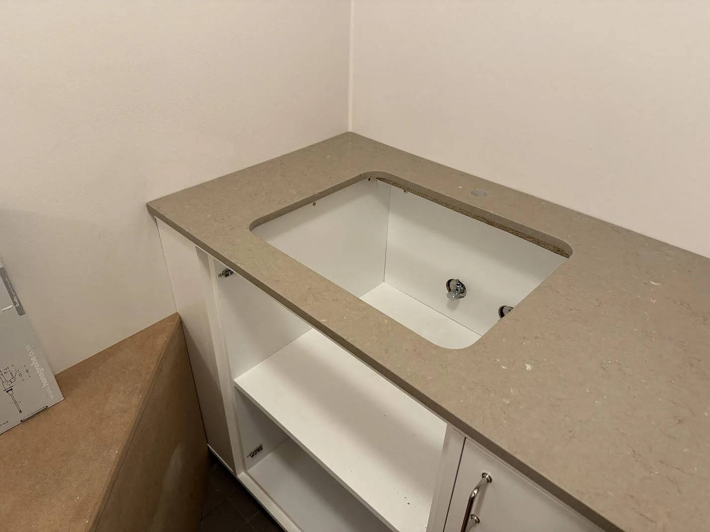 Sidobänk i 20 mm polerad Silestone Coral Clay med rundat diskhourtag och vit stomme under montering i Svendborg.
